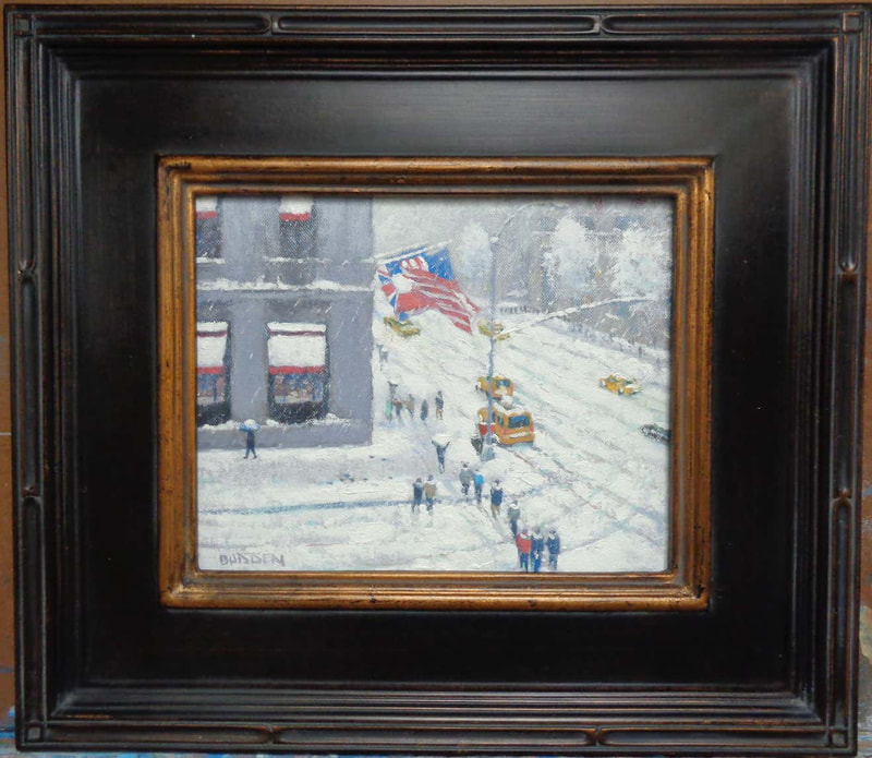 Painting in a black and gold frame of a snowy street corner, a grey building with flags, pedestrians and cars by Michael Budden. Sold by Maser Galleries.